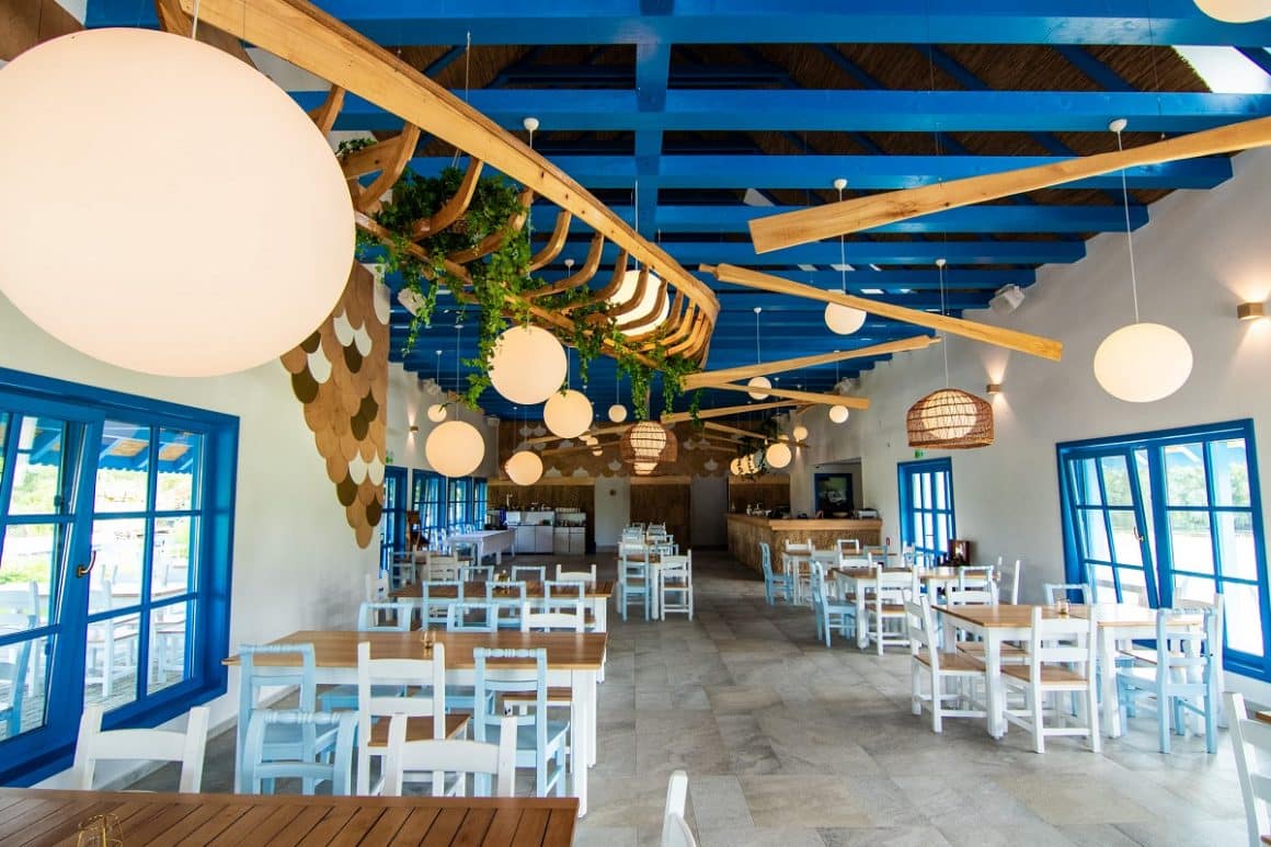 Restaurantul Cherhana Resort, cu tavan din barne albastre, mese albe si ferestre albastre. Unde mâncăm în Delta Dunării