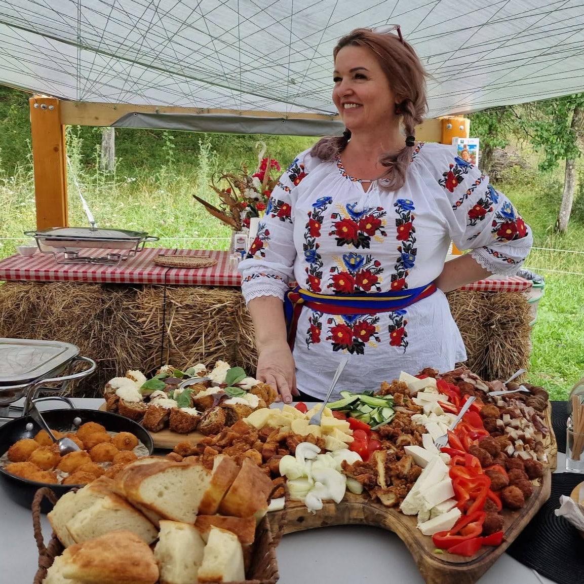 Elena Rus, gazda de la Elena din Deal, servind un platou cu preparate tradiționale din Bistrița-Năsăud