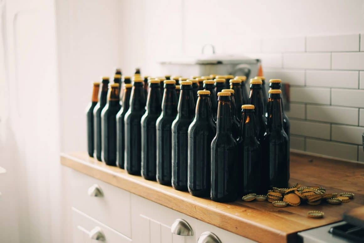 mai multe sticle de bere sunt asezate pe un blat de lemn dintr-o bucătărie