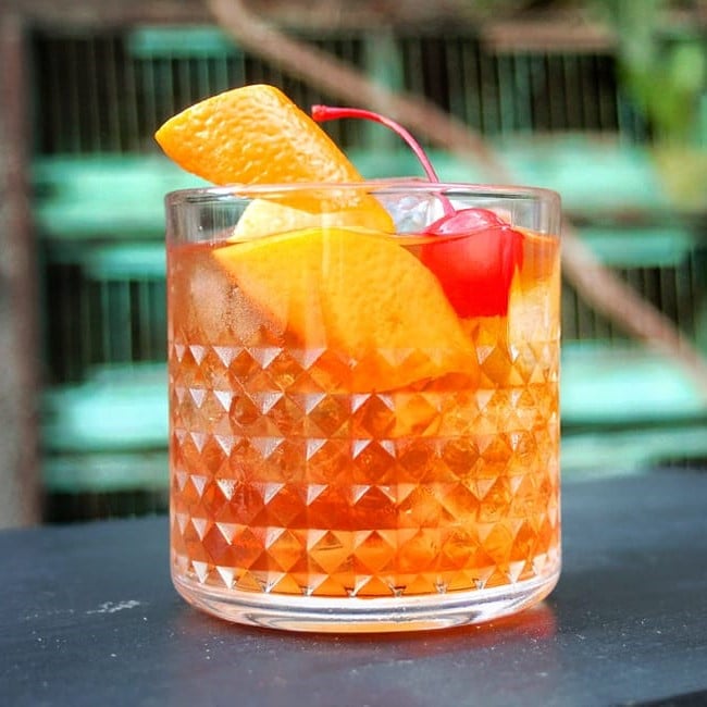 close up cu un cocktail Old Fashioned decorat cu cireasa si felie de citrice, la Gradian Olari, unde să bei cocktailuri la terasă