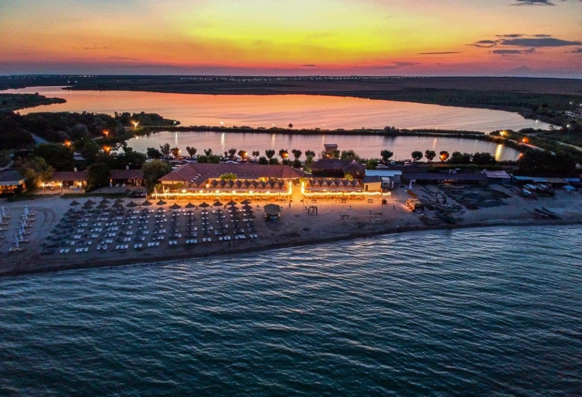 Popasul Pescarilor din Olimp - Cherhanale de pe litoralul românesc. Imagine de ansamblu, cu restaurantul pe plaja, in fata marea iar in spate lacul, la apus