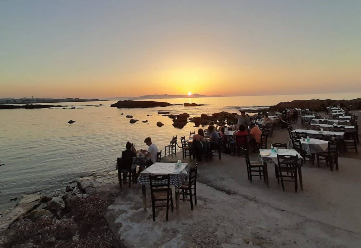 oameni care iau masa pe terasa restaurantului Tahalssino Ageri din Chania, pe malul marii, unde servesc preparate tradiționale din Creta.