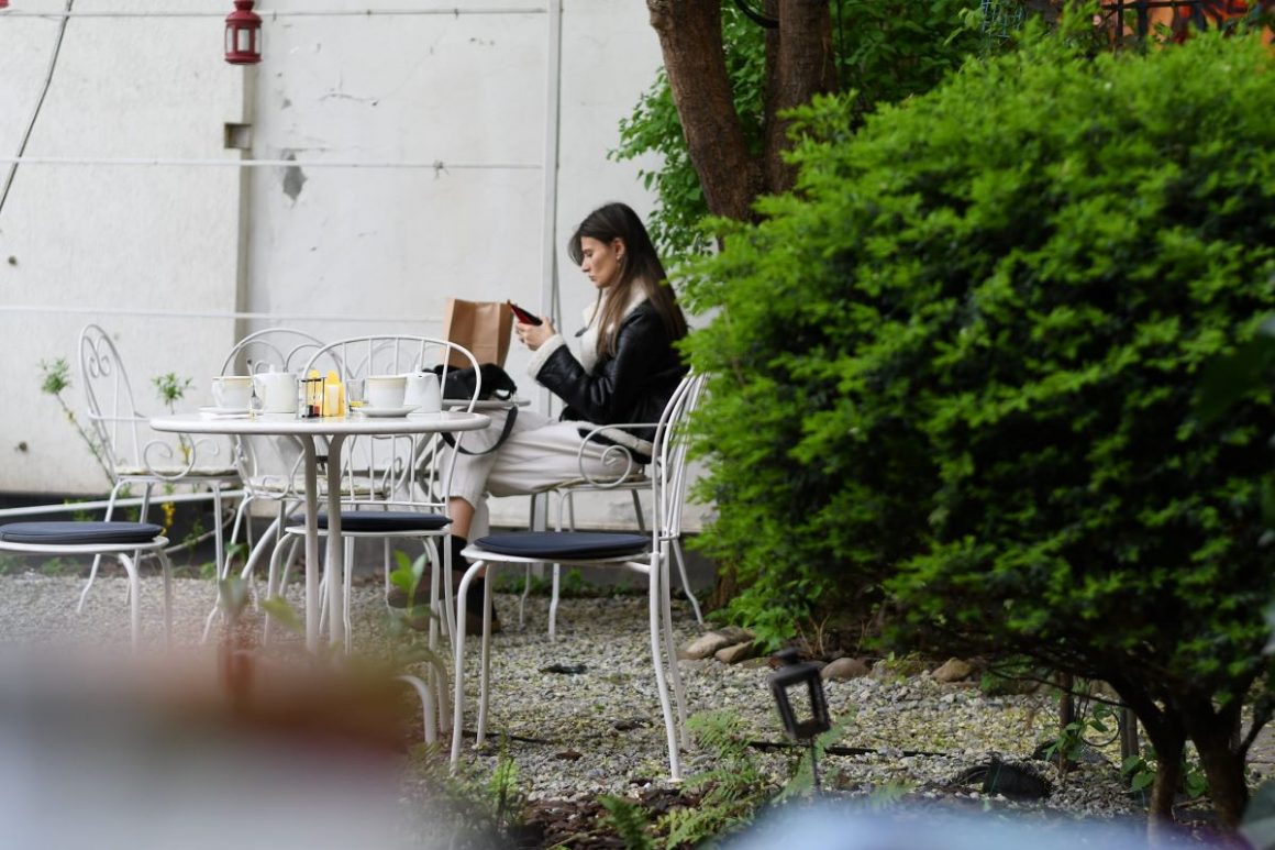 femeie citeste o carte la masa pe terasa de la Ceainăria Green Tea. Grădini din Bucurețti
