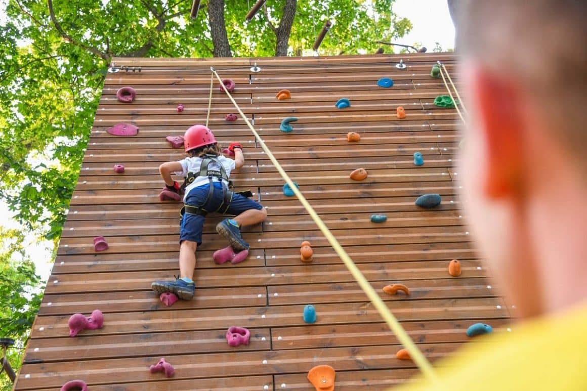 Un copil escaladeaza un panou de catarari la Paradis Land Neptun. Destinații de vară pentru familiile cu copii