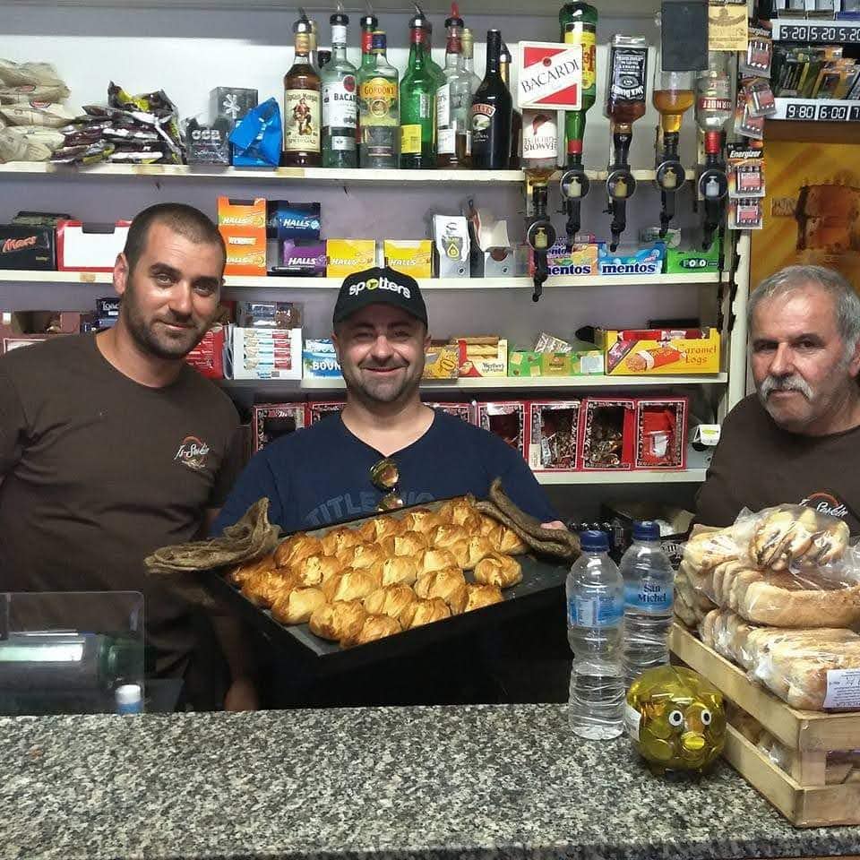 trei barbati pozeaza intr-un magazin alimentar cu o tava de Pastizzi, niste placinte traditionale malteze