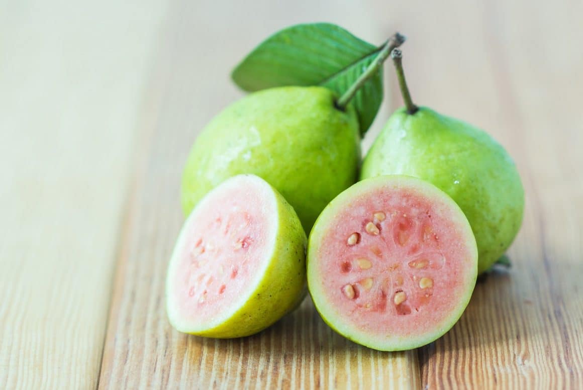 Guava proaspata, intregi si in sectiune, cu coaja verde si pulpa roz. Fructe exotice