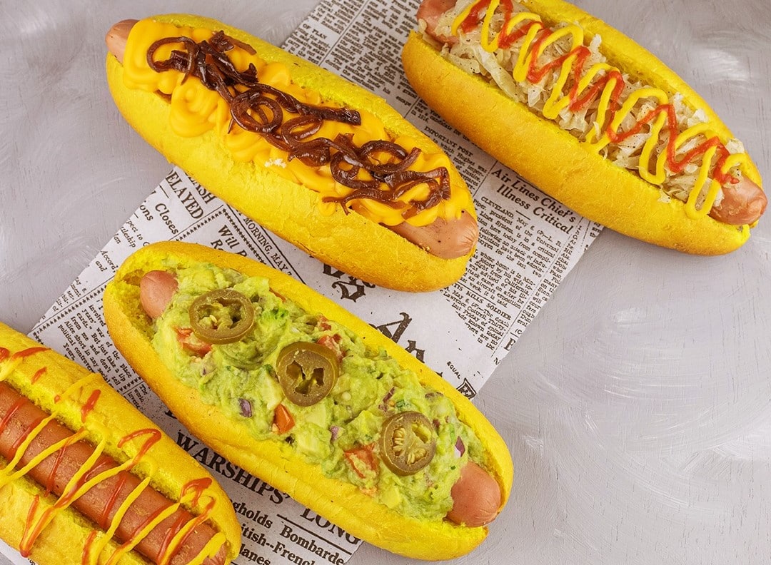 4 tipuri de hot dogs cu fiverse sosuri, asezati pe un ziar, de la Furgoneta Street Chefs București