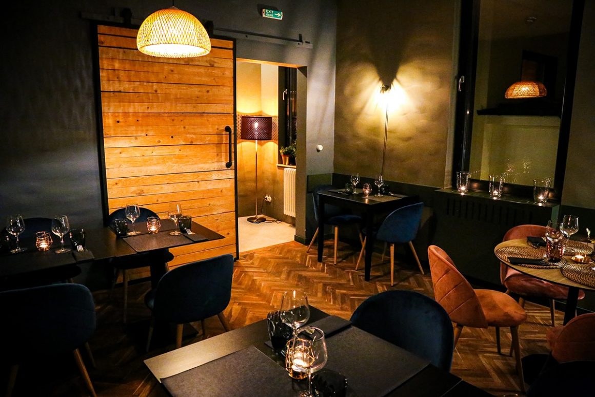 Interiorul restaurantului Ici et la, cu mobilier negru si accente decorative din lemn, iluminat difuz. Restaurante franțuzești București