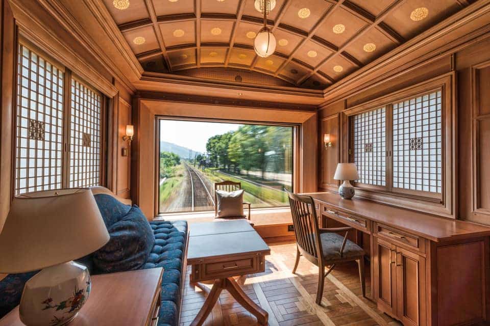 un birou luxos din utimul vagon al unuia dintre trenuri internaționale de lux, cu mobilier de lemn și ferestre mari