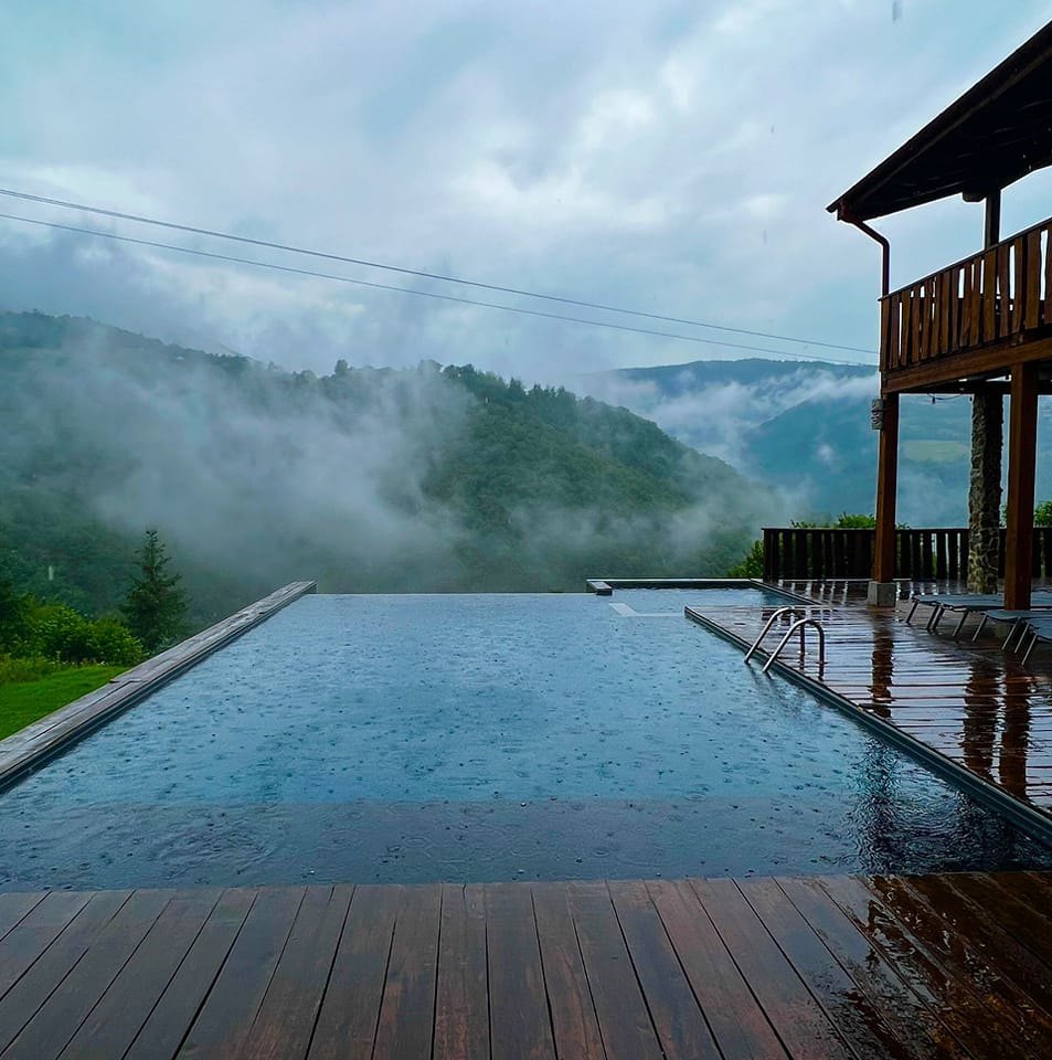 peste piscina infinita a unei vile de la munte ploua, iar deaspura dealurilor din planul secund se ridică ceața