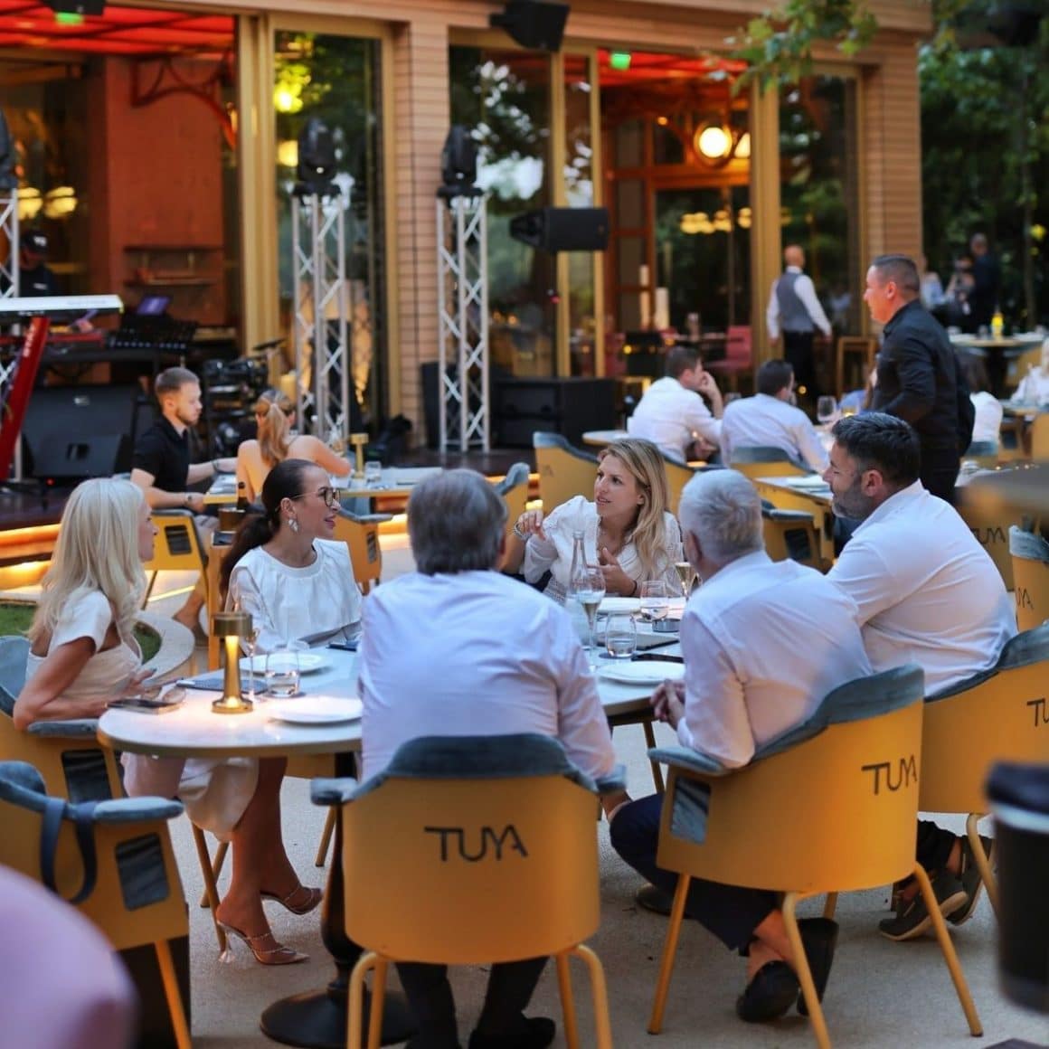 mai multi oameni imbracati in alb sunt la masa restaurantului tuya, unul din locurile cu muzică live din bucuresti