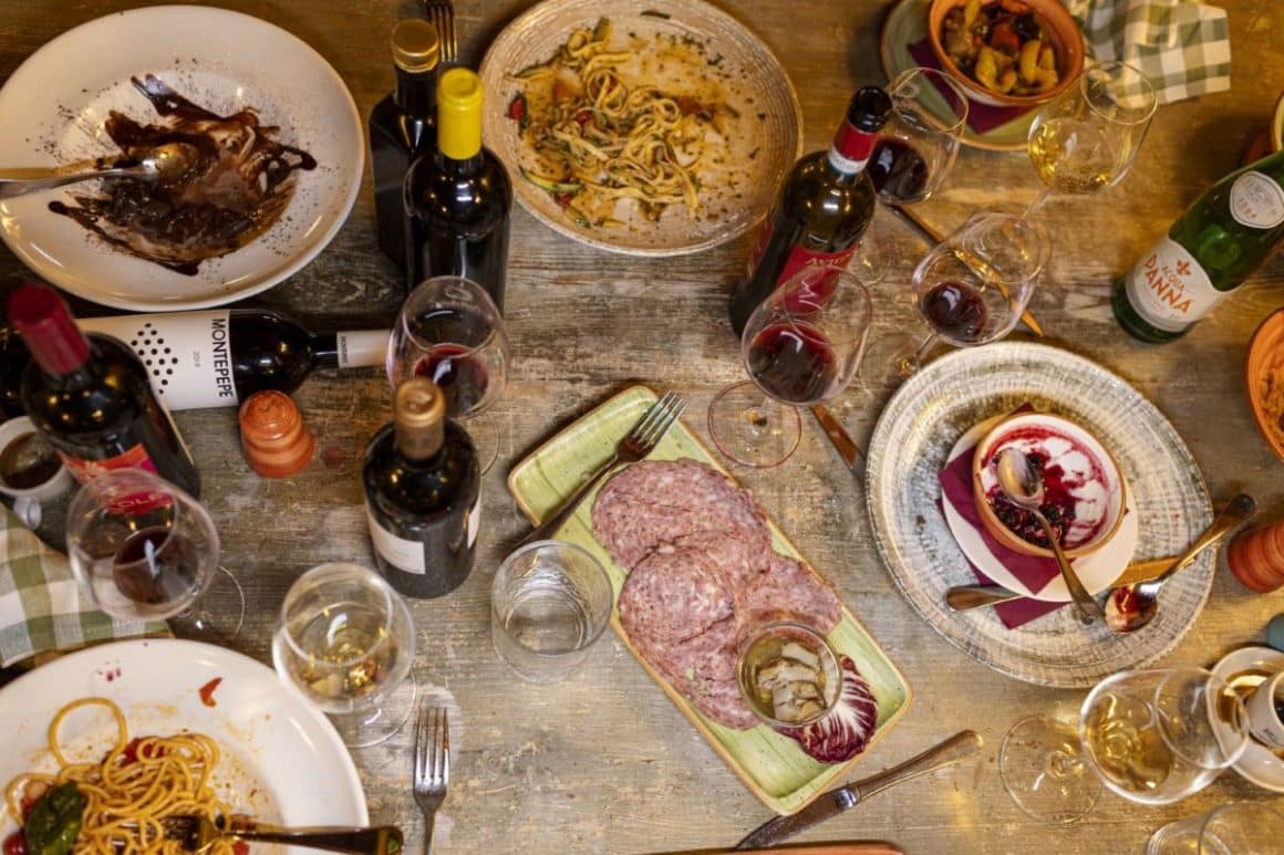mai multe farfurii cu mancarea traditionala din toscana și cateva pahare si sticle asezate pe o masa 