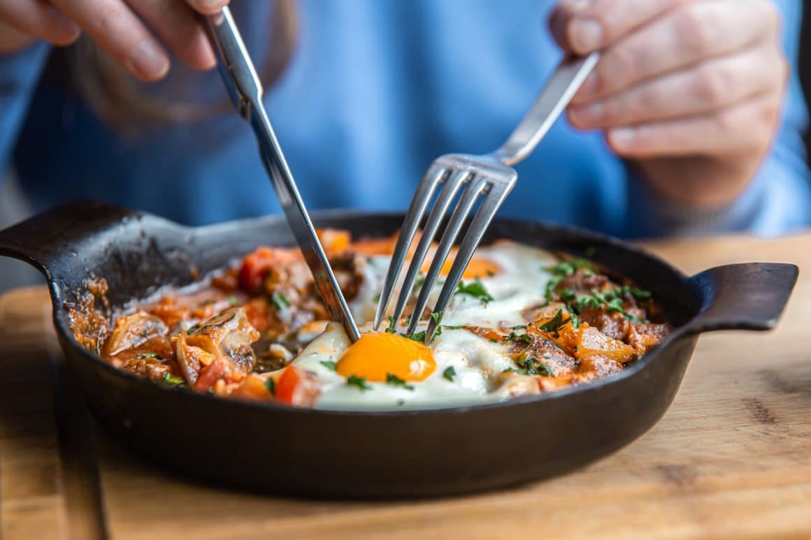Tasty and healthy Shakshuka in a frying pan. Fried eggs with tomatoes, bell pepper, vegetables, and herbs. A middle Eastern traditional dish.