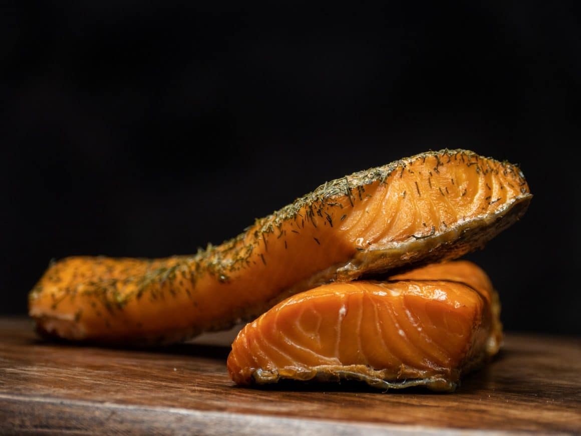 Delicious pieces of smoked salmon on black background