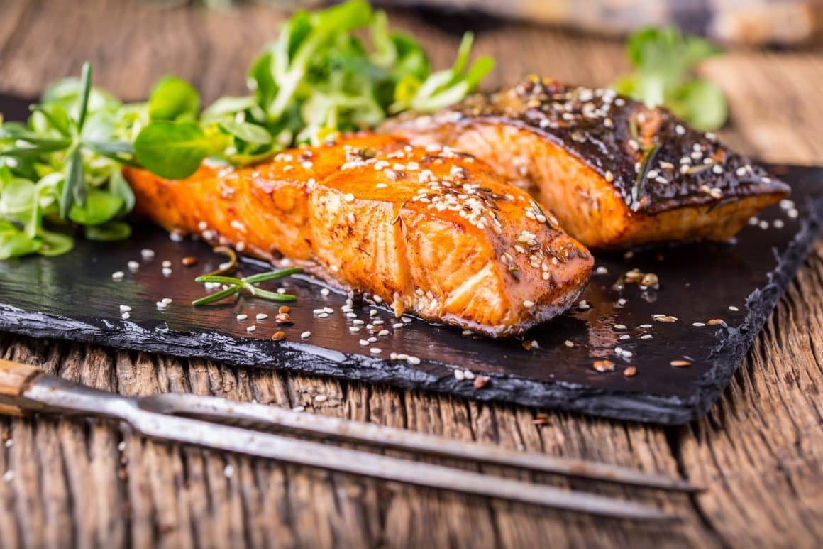 Salmon fillets. Grilled salmon, sesame seeds herb decorationon on vintage pan or black slate board. fish roasted on an old wooden table. Studio shot. CUm se gătește somonul