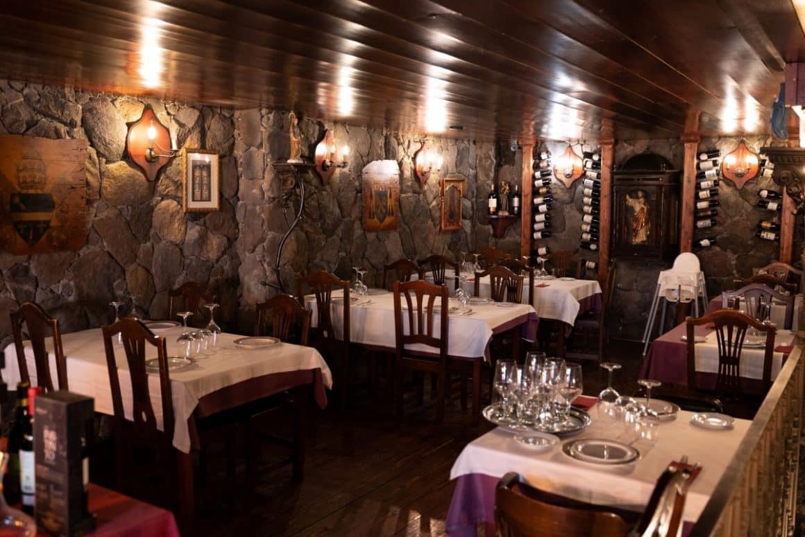 interiorul clasic al restaurantului Tasca El Obispado, cu mese și scaune de lemn și pereții decorați cu piatra naturala