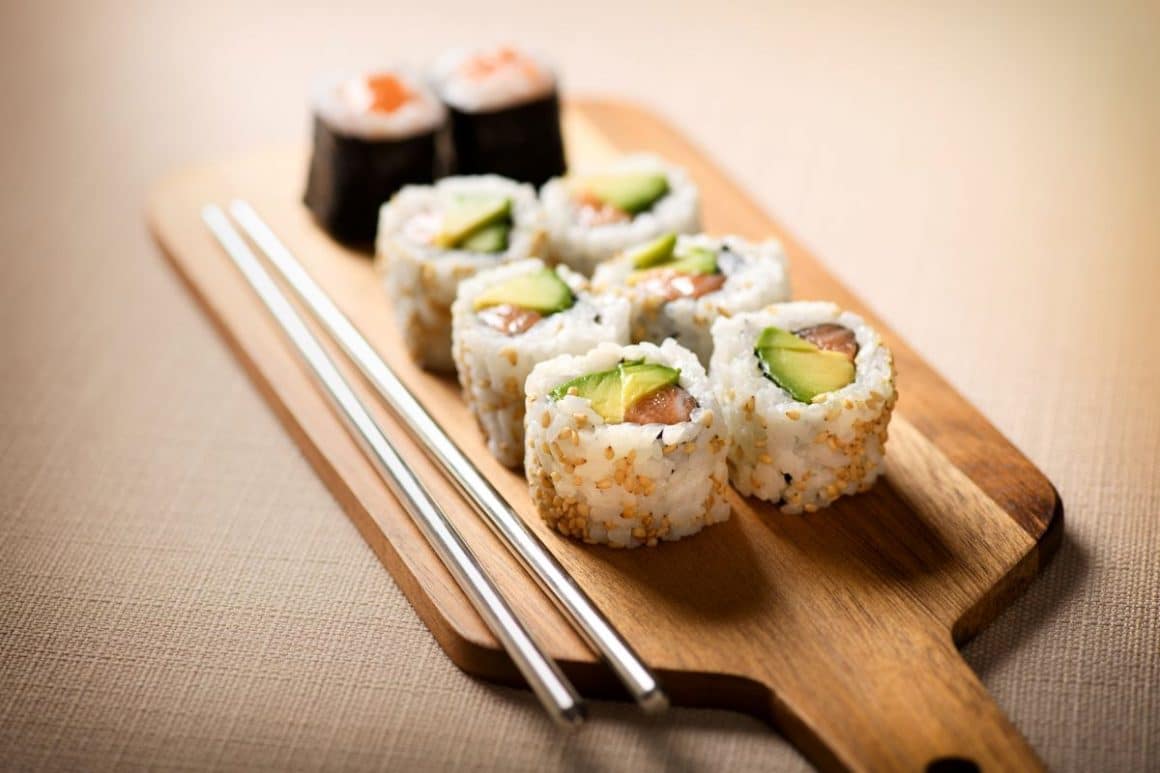un platou de lemn cu sushi uramaki și doua rulouri maki și betiosare chinezesti