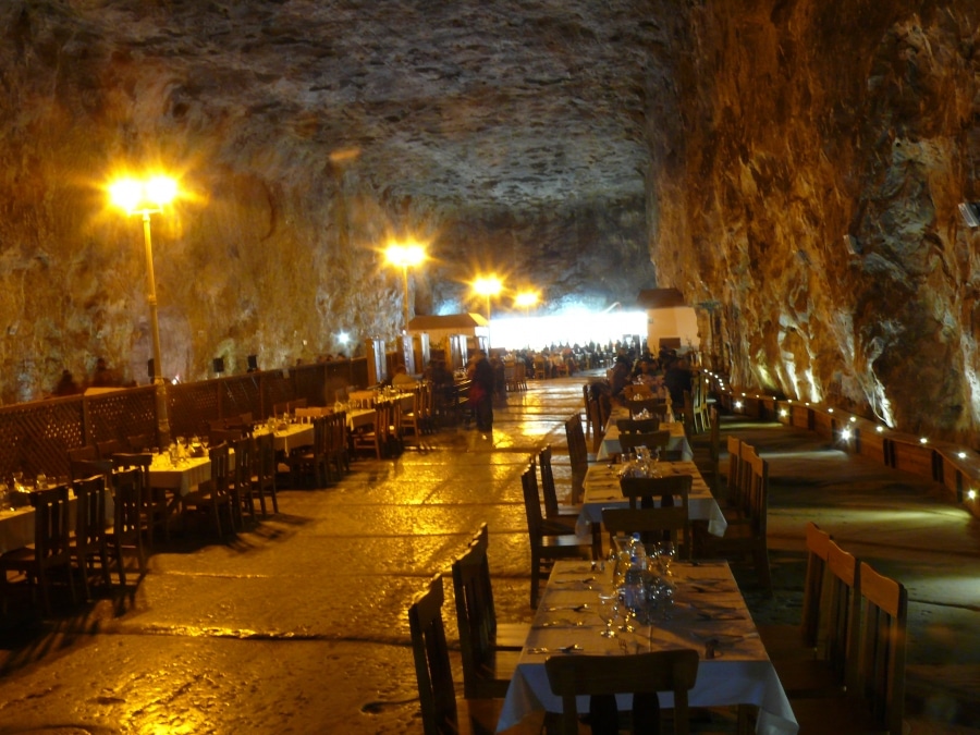 sala de mese a unui restaurant din interiorul unei saline din romania, cu mese de lemn și lumină difuză