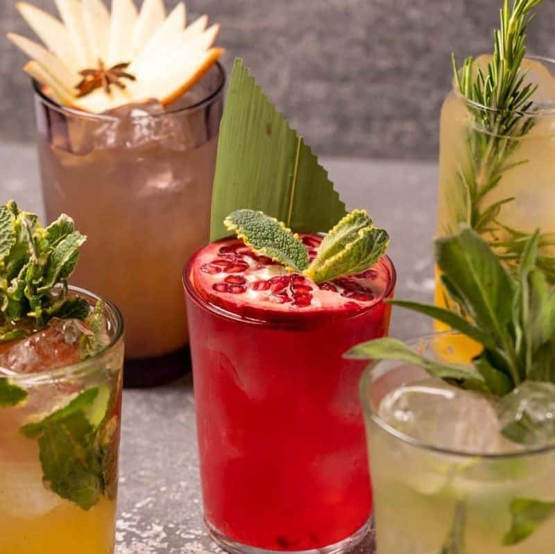 mai multe pahare de cocktail sunt ornate cu frunze verzi proaspete