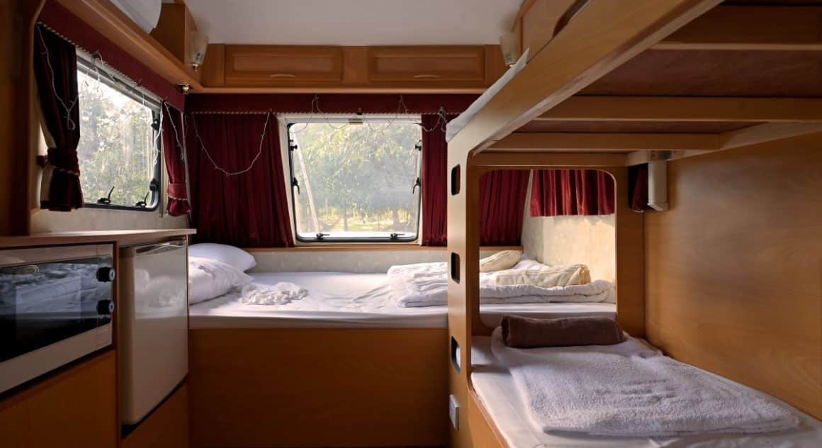 un dormitor de autorulotîă, cu paturi suprapuse si cearceafuri albe