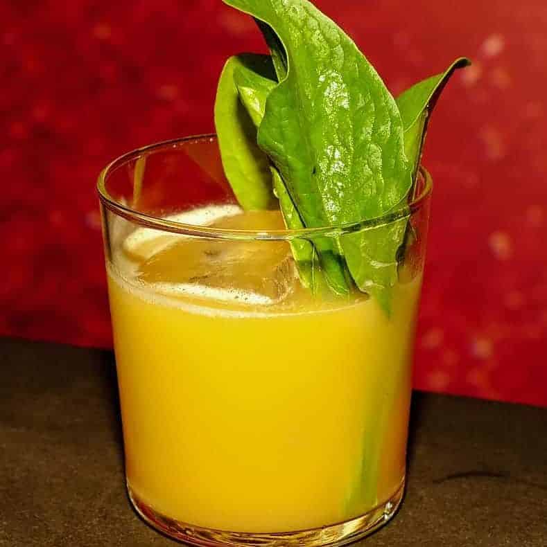 un cocktail potrocaliu este asezat intr-un pahar scurt cu frunze de busuioc deaspura. Fix me a drink - cocktail baruri din București