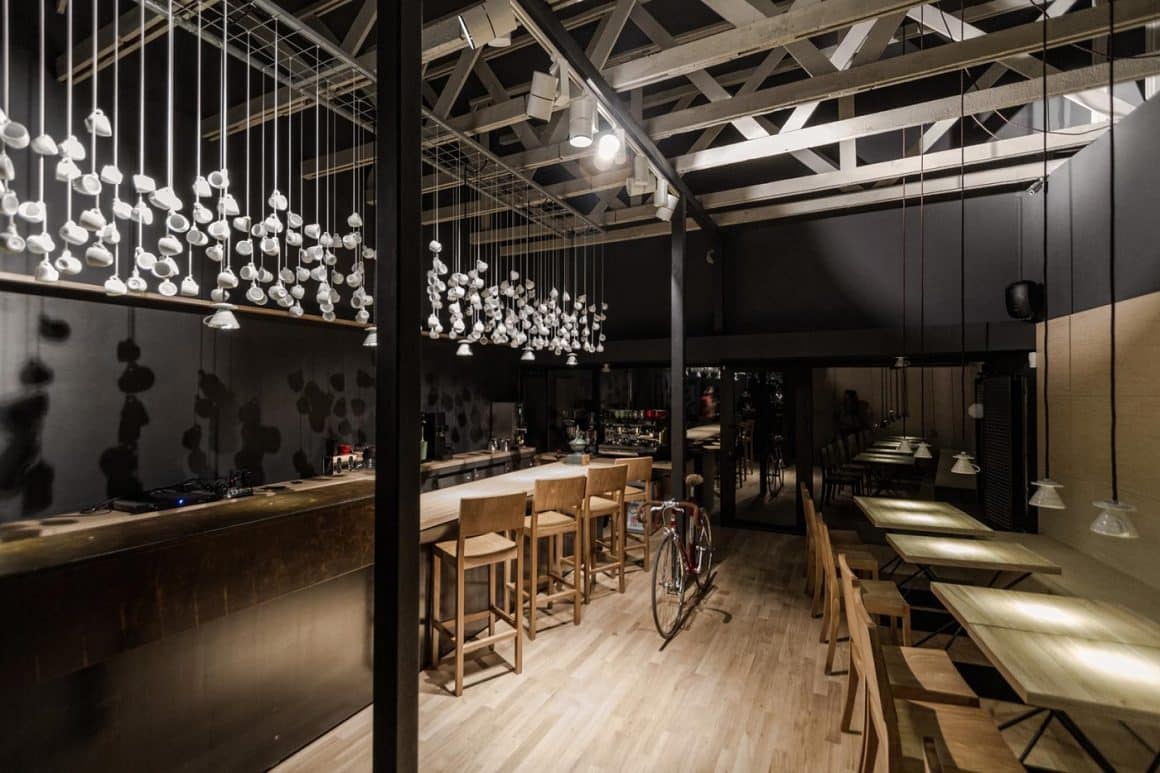 Origo, una din cafenele moderne unde poți lucra, ceorat cu cescute atrnate, mobilier din lemn si pereto negrii