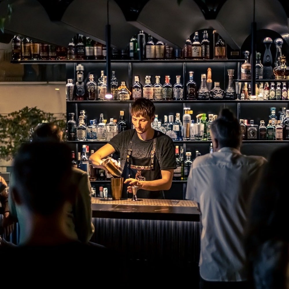 Barman serveste la bar la The Owl Cocktail Bars