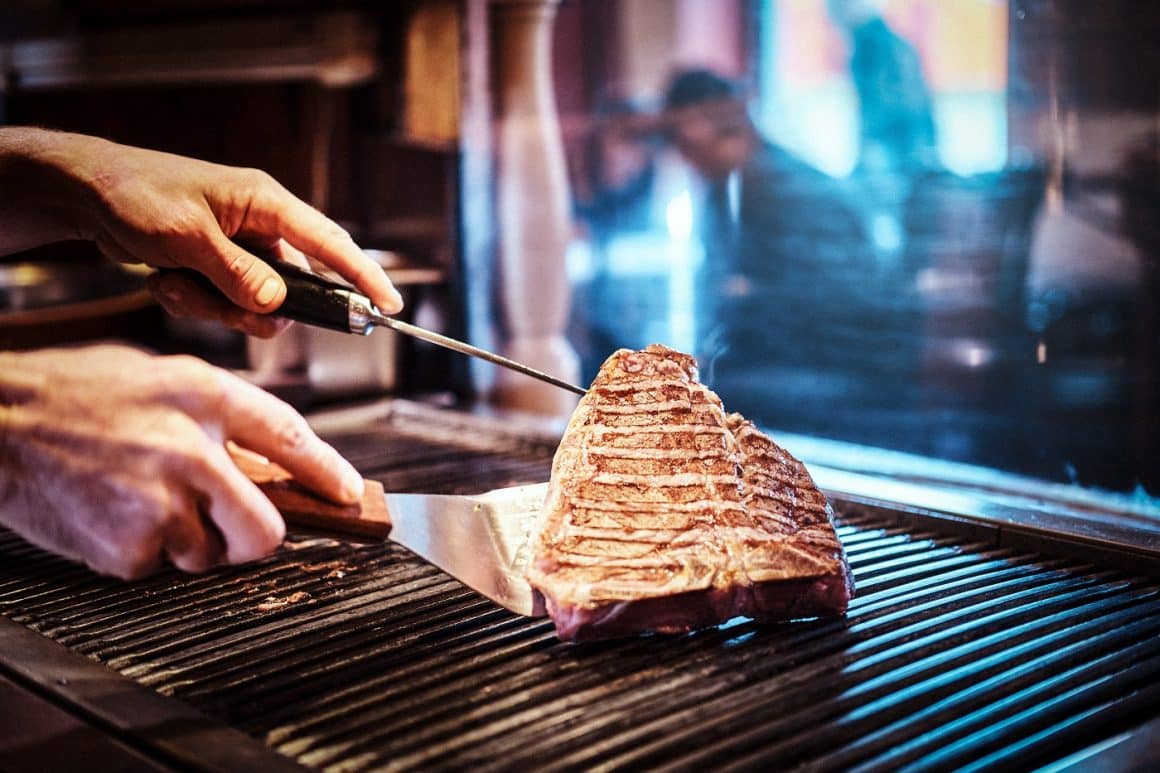 Close-up image of a cooking delicious meat steak on a grill in a restaurant kitchen. Top steahouse din București