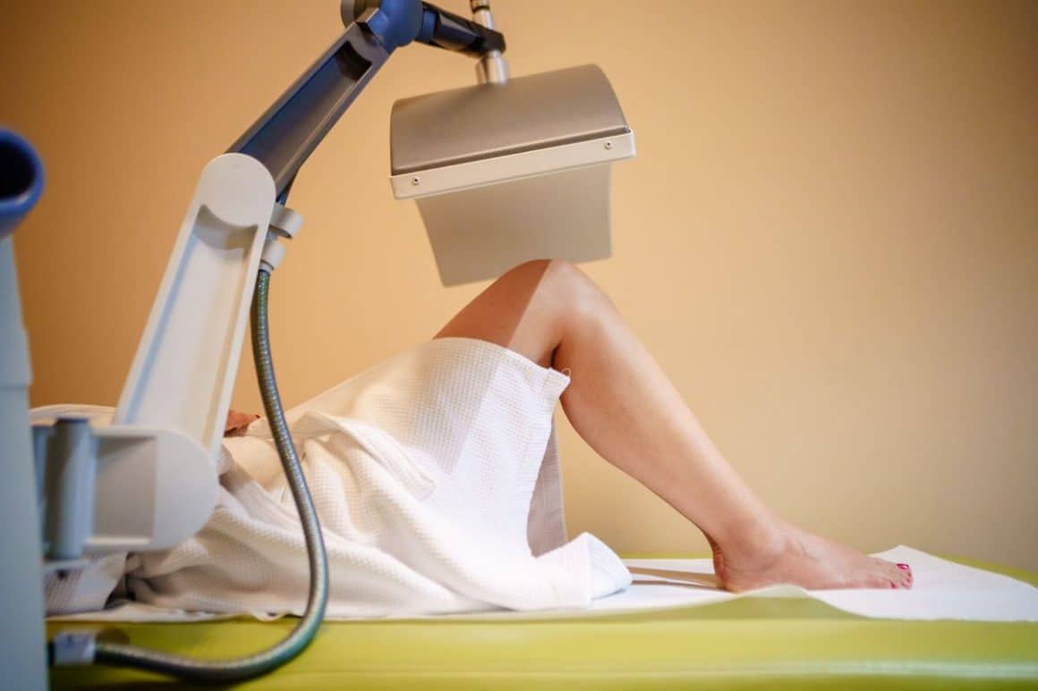 un aparat medical executa o procedură clinică pe picioarele unei femei cu picioarele flexate