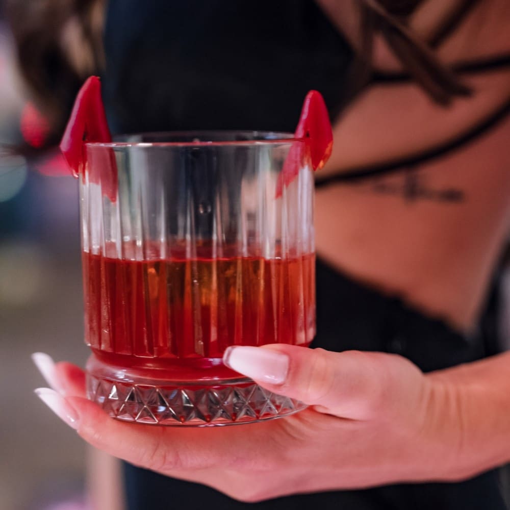 pahar de cocktail negroni decorat cu 2 bucati de ardei iute care seamana cu 2 cornite