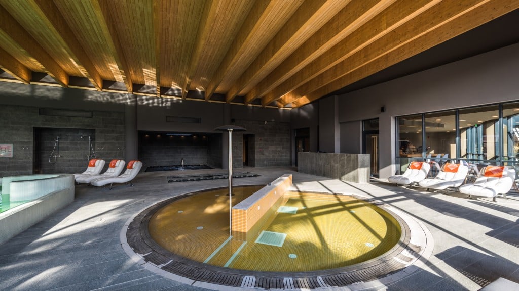 mai multe chez-longuri sunt asezate pe marginea unei piscine dintr-un spa la Balvanyos Resort, Grand Santerra Spa