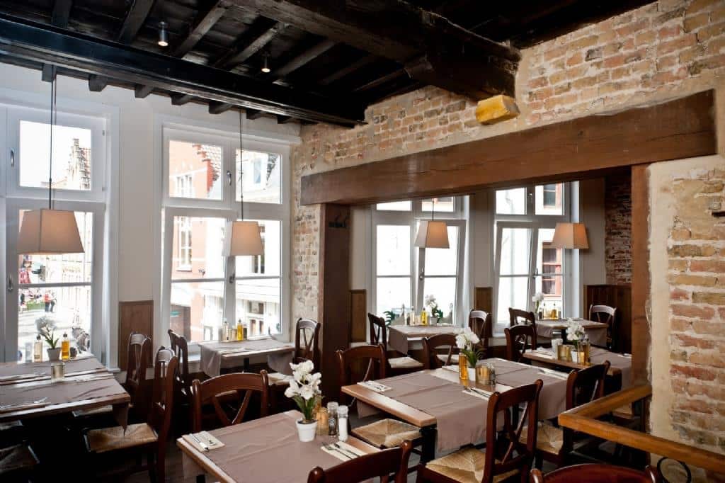 interiorul restaurantului poules moules din Bruges, cu decor clasic, cu cărămidă aparentă și mobilier de lemn