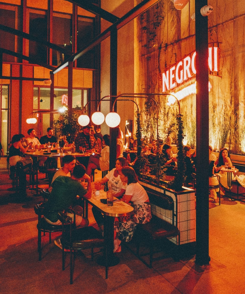 oameni asezati seara la mese in curtea de la Negroni Aperitivo Bar București