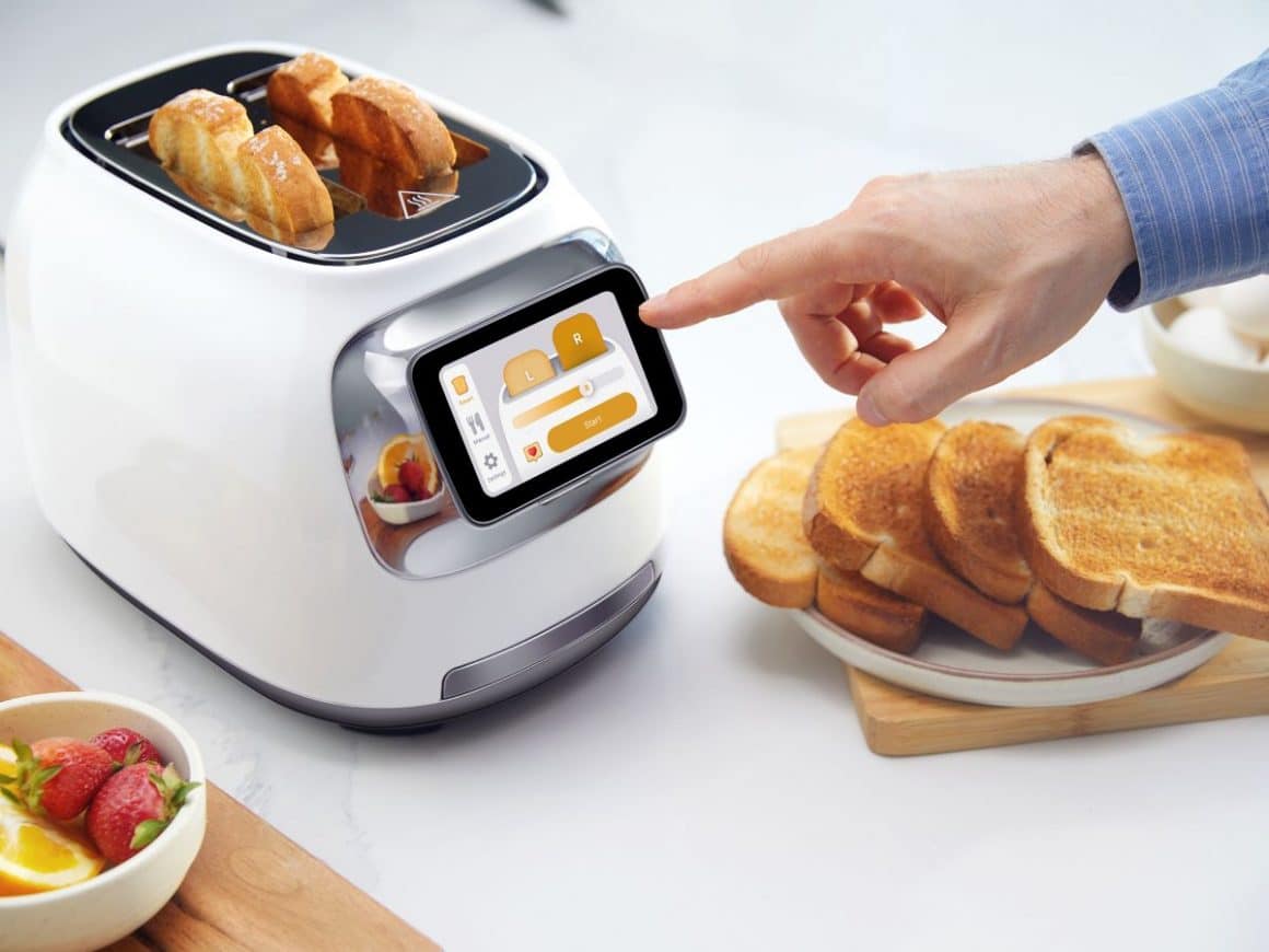 o mana de barbat apasa pe displayul unui toaster inteligent, unul dintre cele mai noi gadgeturi de bucatarie