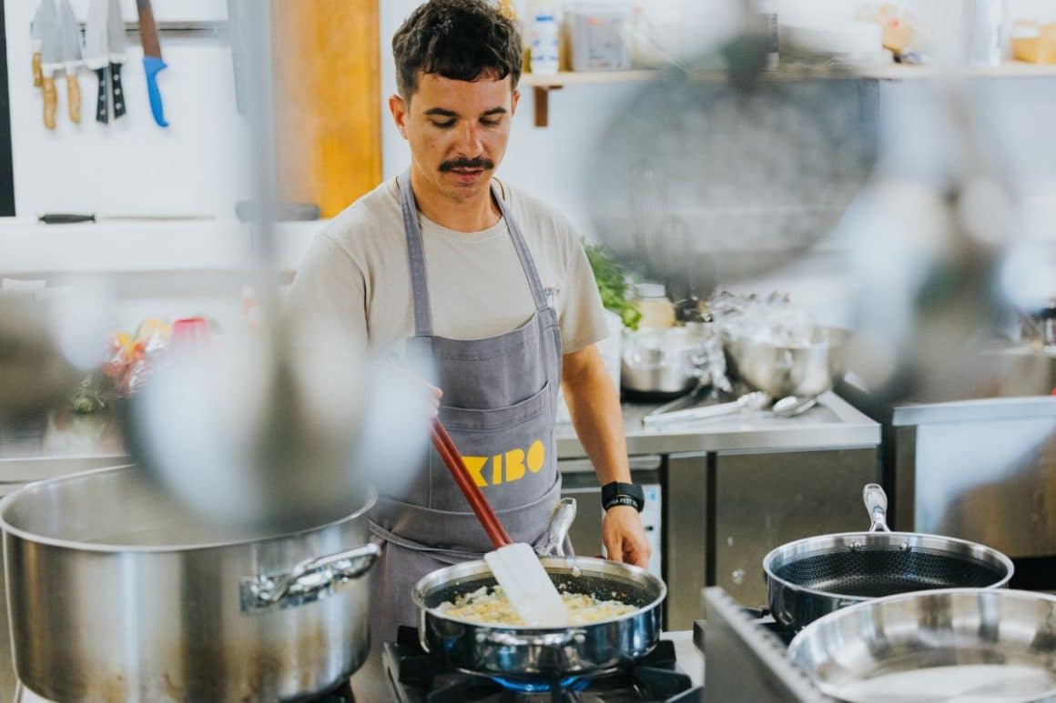 un bucătar personal amestecă într-o tigaie cu rissotto, într-o bucătărie profesională