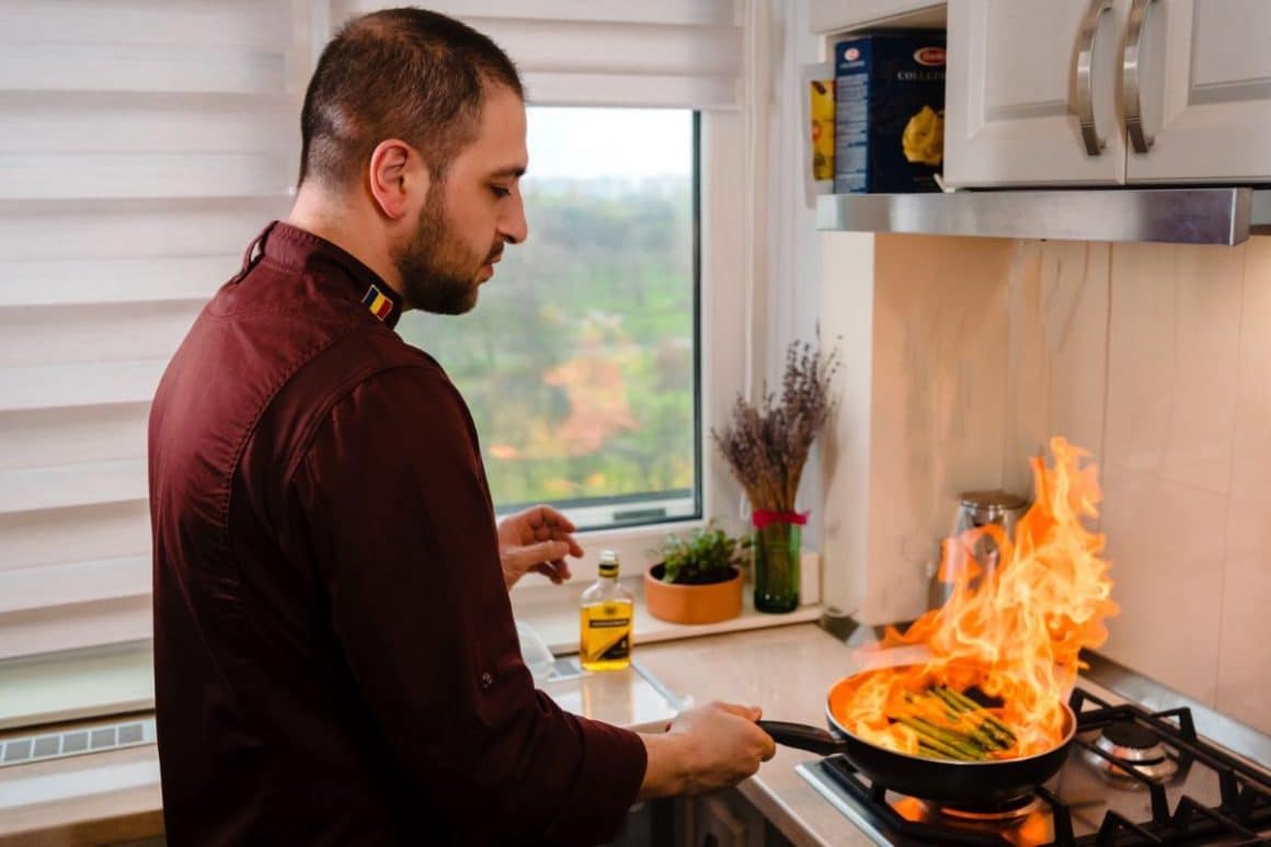 un bucătar personal flambează o porție de sparanghel într-o bucătărie de casă