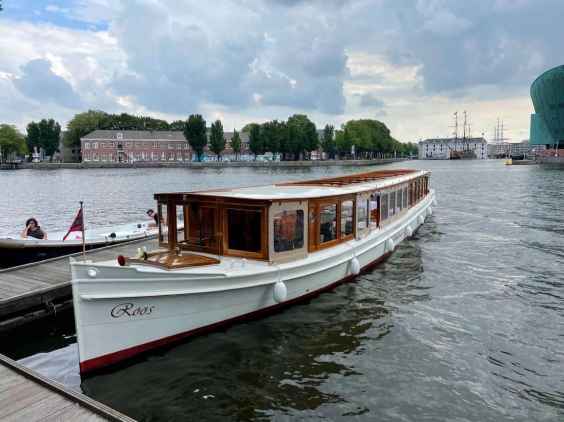 o barcă pentru croaziere turistice este andocată la malul unui canal din amsterdam