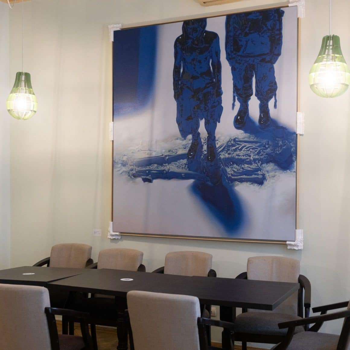 un tablou modern este asezat pe peretele din dreptul unei mese de restaurant