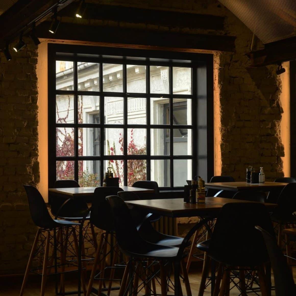 interiorul unui restaurant scandinav cu câteva mese in fata unui geam mare