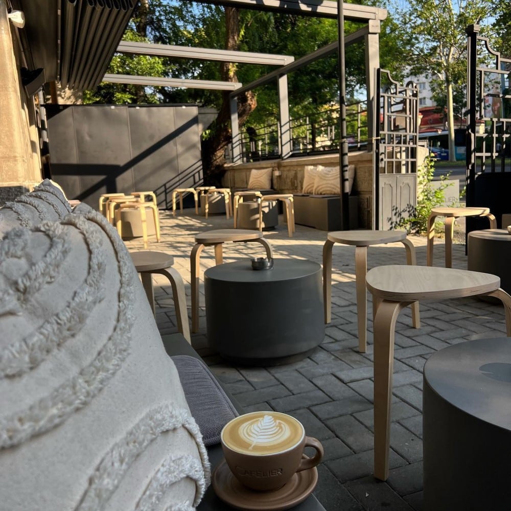 mobilierul exterior din grădina unei cafenele micuțe din bucuresti, cu scaune de lemn ți măsuțe joase rotunde