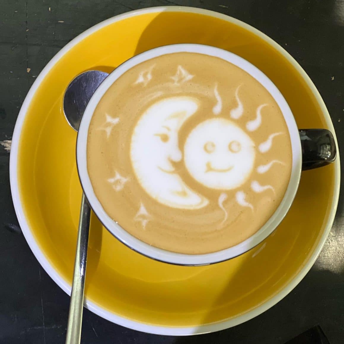 ceasca de cafea fotografiata de sus cu imagine soare si luna facuta din lapte