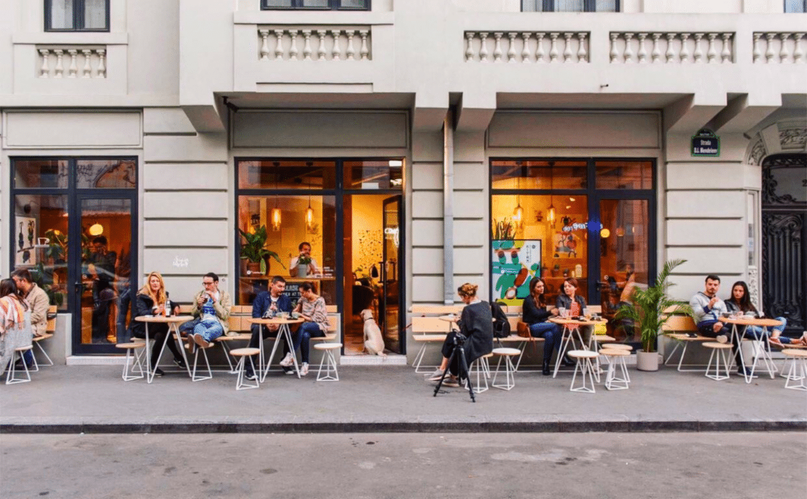 Oameni la mese afara pe trotuar in fata cafenelei M60, unul din localuri cu aer scandinav din București