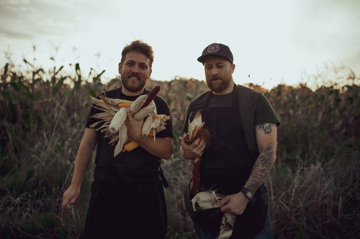 Chef Alex Iacob și chef Cristi Dăscăleanu, intr-un lan de porumb, tin porumb in mana