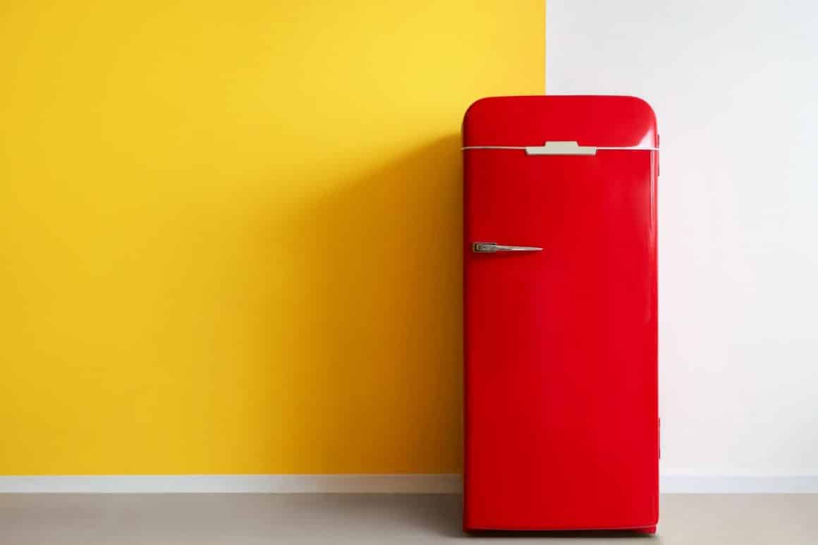 un frigider roșu este așezat lângă un perete jumătate galben, jumătate alb