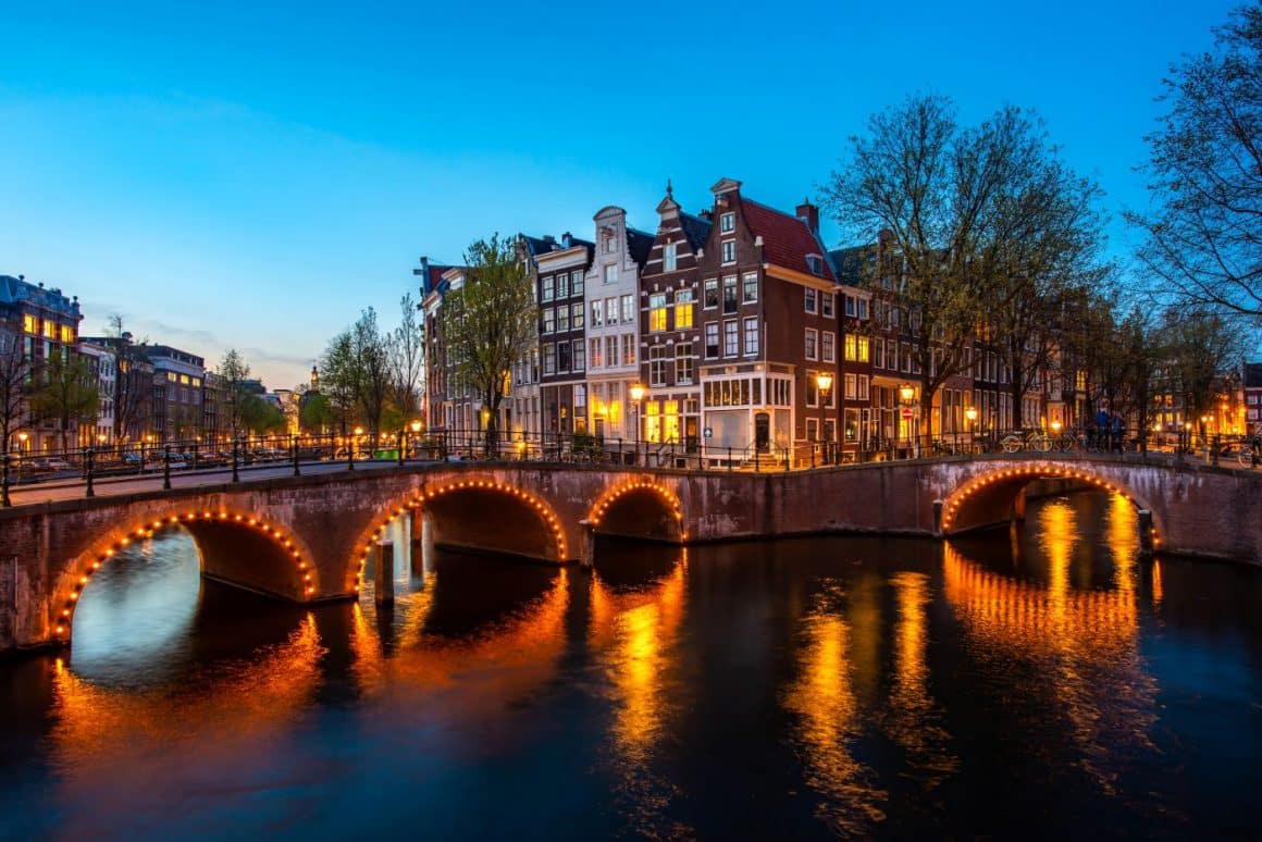 o intersecție a două canale cu poduri luminate, în amsterdam