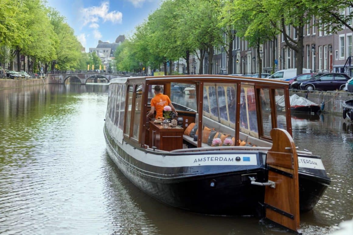 o barcă pentru croaziere turistice este andocată la malul unui canal din amsterdam