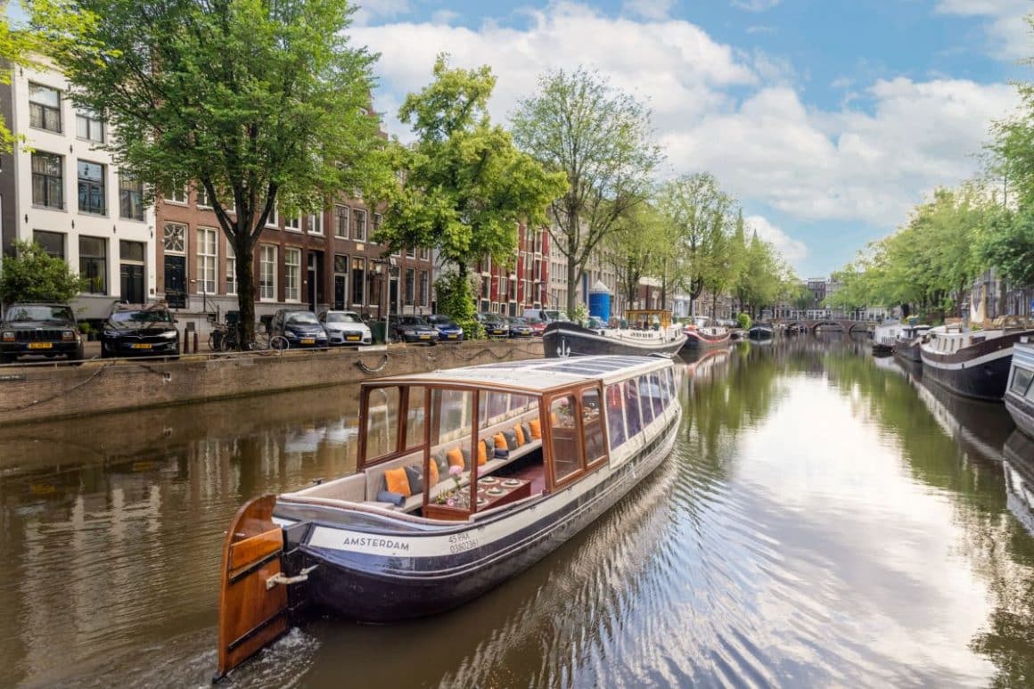 o barcă pentru croaziere turistice plutește pe unul dintre canalele din amsterdam