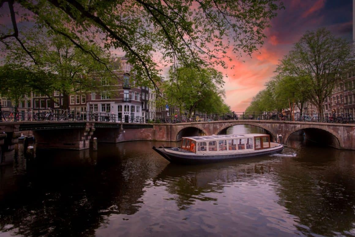 o barcă pentru croaziere turistice trece pe sub podurile de pe nul dintre canalele din amsterdam