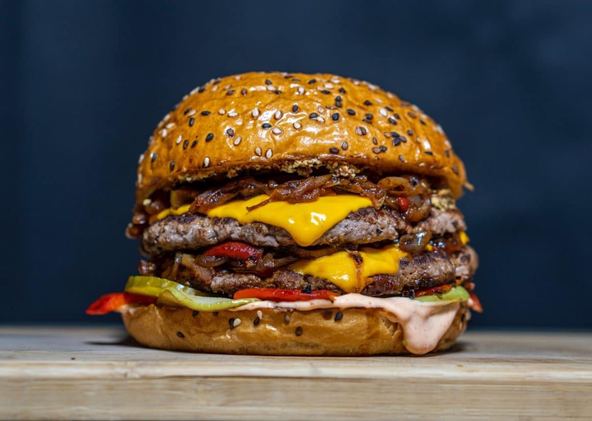 close up cu un burger cu ceapa caramelizată