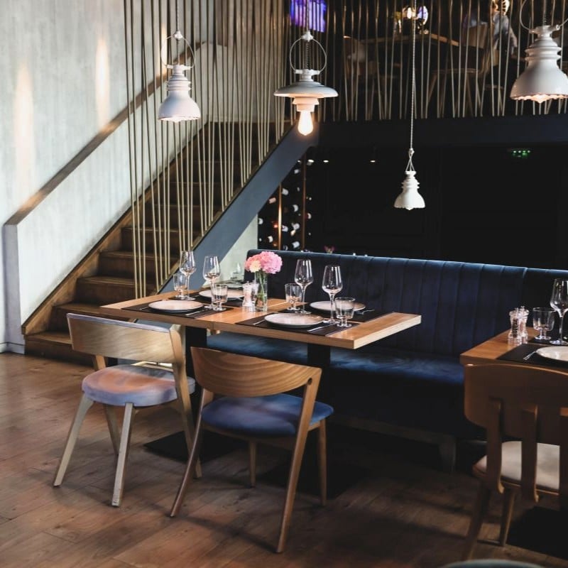 masa din lemn cu scaune retro si o bancuta de catifea neagra la Haute Pepper, unul din restaurante cozy din București
